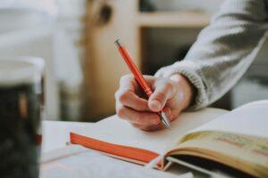 A lady sat at a table writing in a journal
